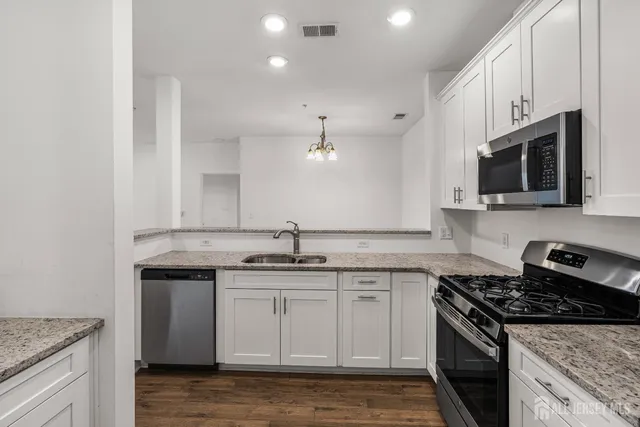 a kitchen with stainless steel appliances granite countertop a sink stove and microwave