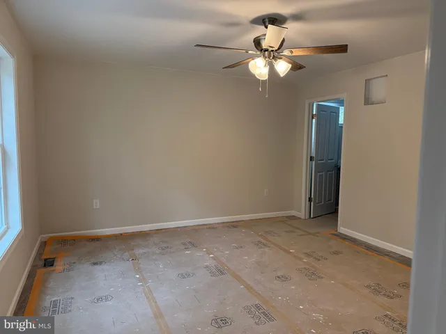 an empty room with a chandelier fan and a window