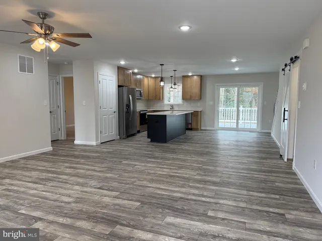 a large kitchen with stainless steel appliances a large counter top a refrigerator and a chandelier