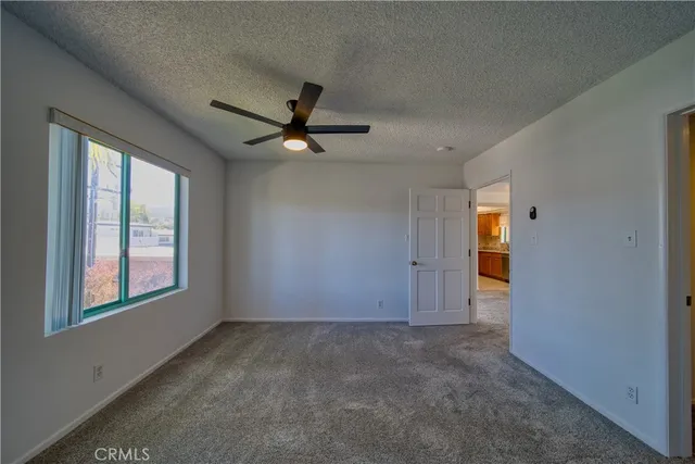 an empty room to ceiling fan and windows