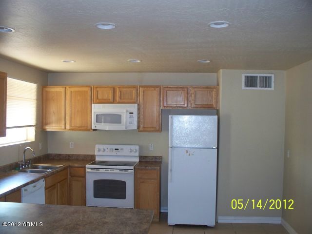 4837 West Osborn Road Phoenix, AZ 85031 - Photo 10 of 14 a kitchen with a refrigerator and a stove top oven