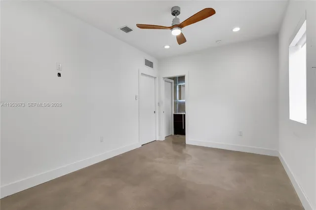 an empty room with ceiling fan and window