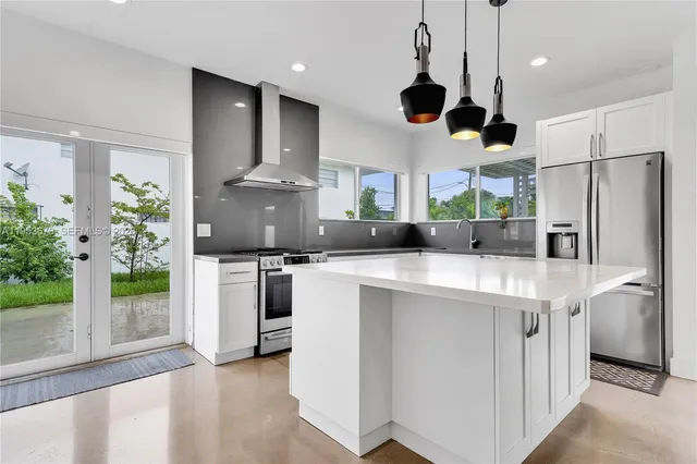 a kitchen with stainless steel appliances granite countertop a refrigerator a stove a microwave oven a sink with a dining table and chairs