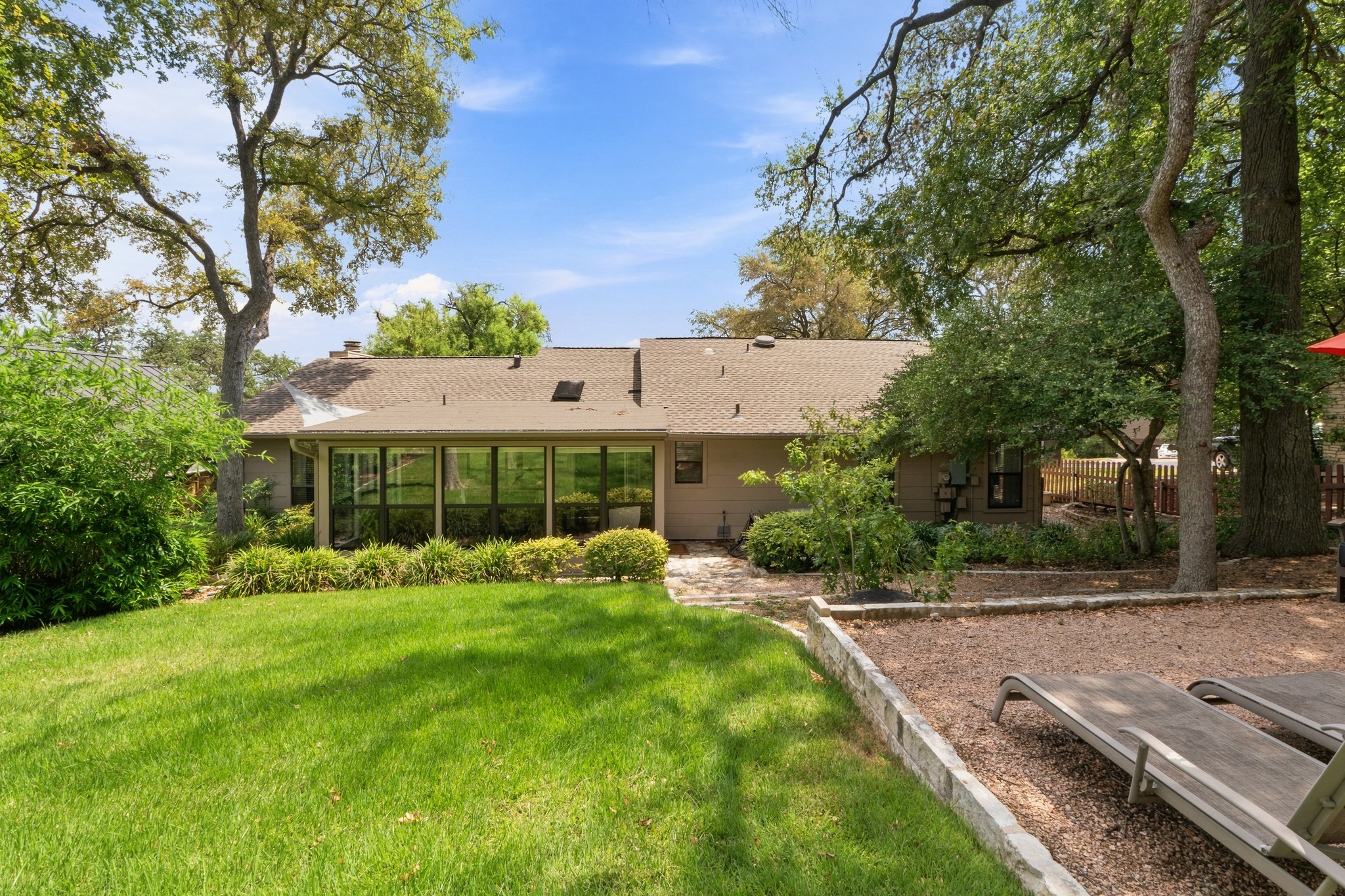 1904 Stoneridge Road Austin, TX 78746 - Photo 34 of 40 Rear exterior showcases the enclosed sunroom and the home’s seamless connection to the landscaped yard.
