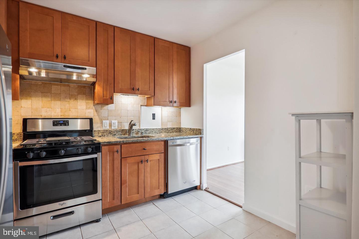1111 University Boulevard West, Unit 1003 Silver Spring, MD 20902 - Photo 17 of 38 a kitchen with granite countertop wooden cabinets and stainless steel appliances