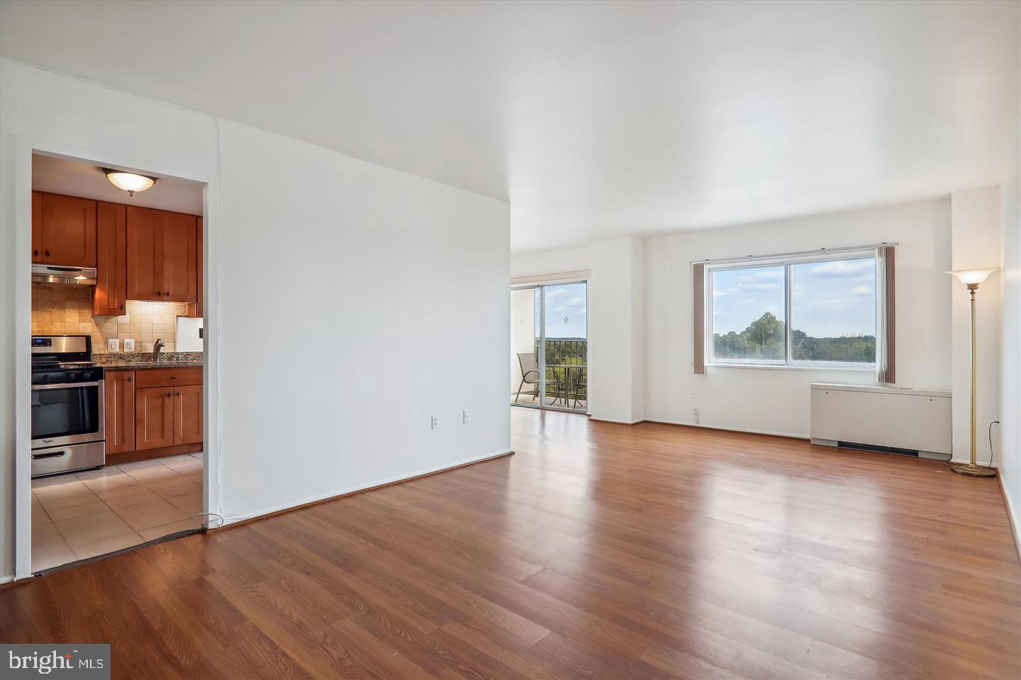 1111 University Boulevard West, Unit 1003 Silver Spring, MD 20902 - Photo 20 of 38 an empty room with wooden floor windows and kitchen view