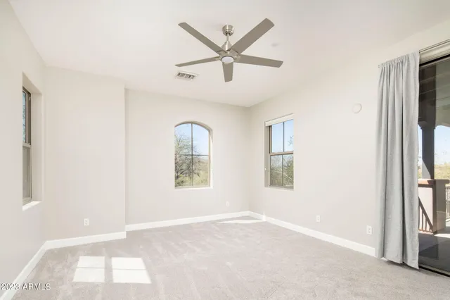an empty room with windows and ceiling fan