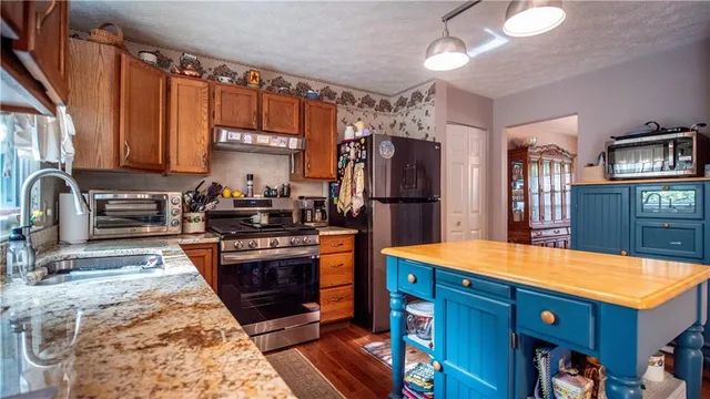 a kitchen with stainless steel appliances granite countertop a stove a sink dishwasher and cabinets with wooden floor