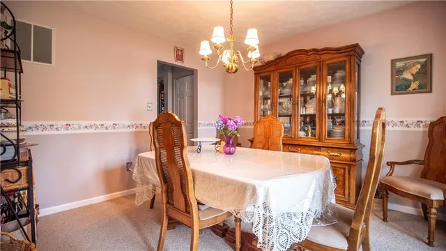 a view of a dining room with furniture a chandelier and large windows