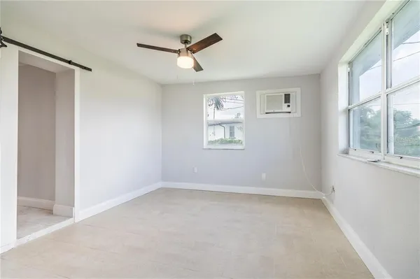 an empty room with windows and fan