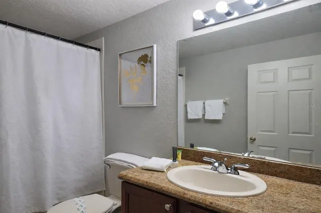 a bathroom with a granite countertop sink toilet and a mirror