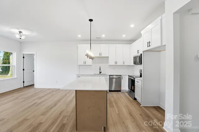a large kitchen with stainless steel appliances sink a refrigerator and a wooden floor