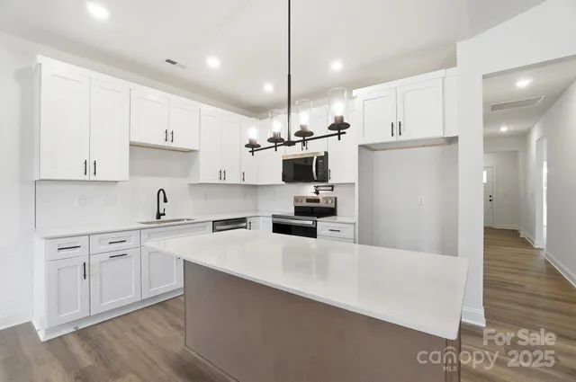 a kitchen with kitchen island a white counter top space cabinets and stainless steel appliances