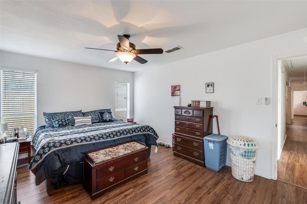 1509 Springbrook Street Corinth, TX 76210 - Photo 13 of 24 a bedroom with a bed and a chandelier