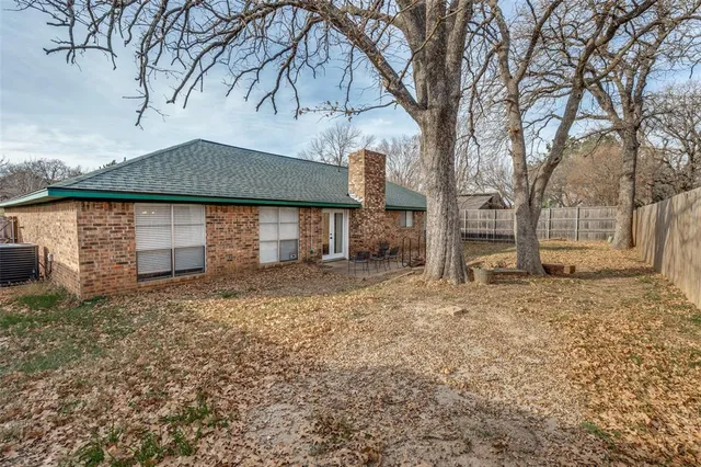 a backyard of a house with large trees and barbeque oven