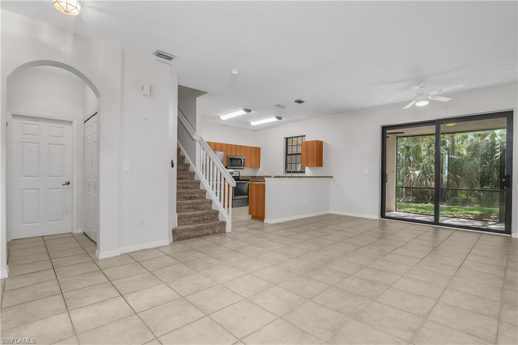 15186 Summit Pl Circle Naples, FL 34119 - Photo 26 of 37 Unfurnished living room featuring ceiling fan, arched walkways, and light tile patterned floors