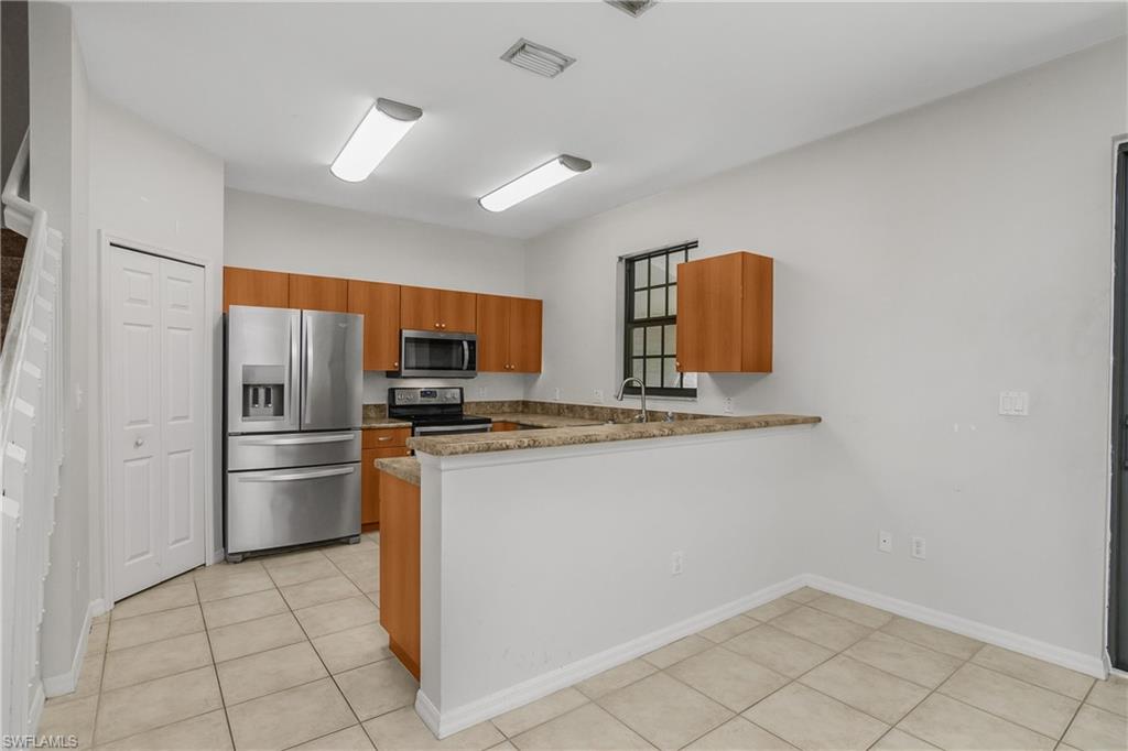15186 Summit Pl Circle Naples, FL 34119 - Photo 5 of 37 a kitchen with stainless steel appliances granite countertop a refrigerator a stove a sink and a microwave