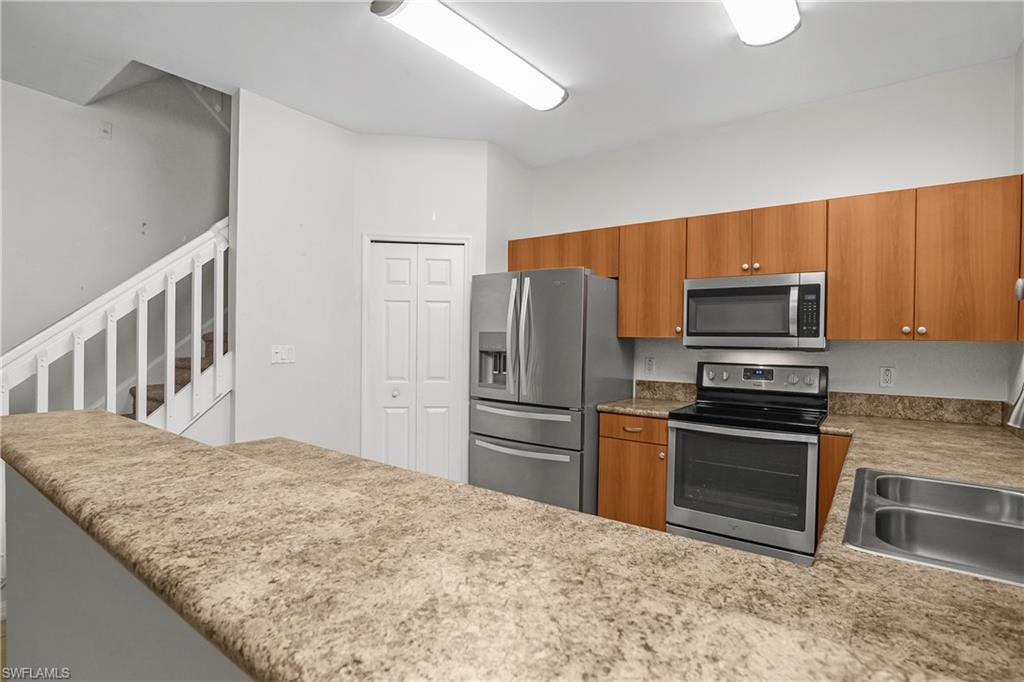 15186 Summit Pl Circle Naples, FL 34119 - Photo 7 of 37 a kitchen with granite countertop a refrigerator and a stove top oven