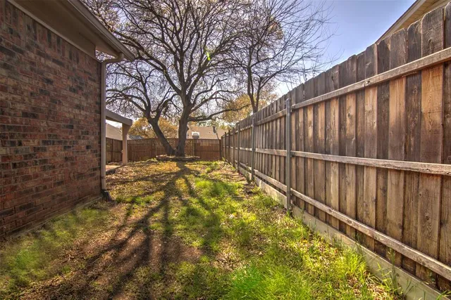 a view of backyard with wooden fence and large trees