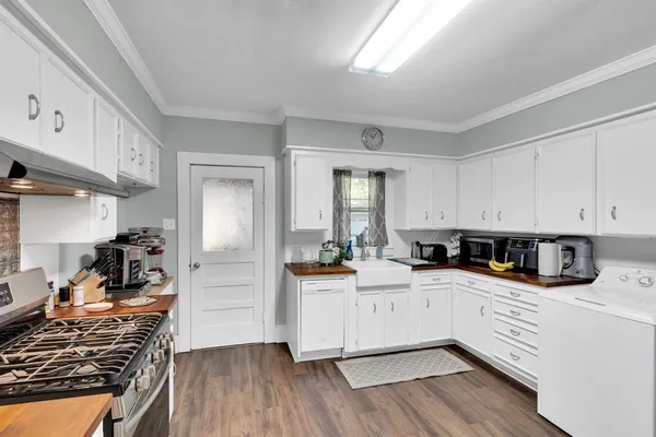 a kitchen with stainless steel appliances a stove top oven a sink a refrigerator white cabinets and wooden floor