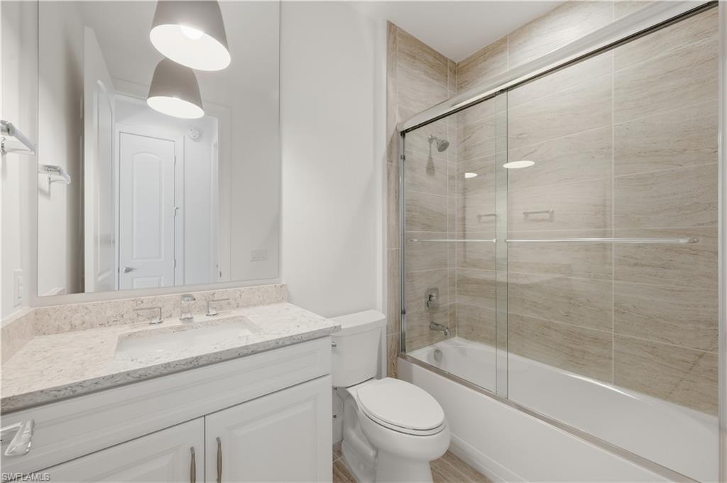 7733 Jacaranda Lane Naples, FL 34114 - Photo 16 of 38 a bathroom with a granite countertop sink a toilet and shower