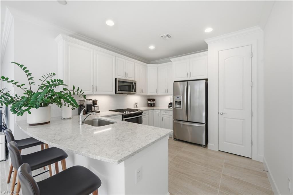 7733 Jacaranda Lane Naples, FL 34114 - Photo 10 of 38 a kitchen with a refrigerator a stove a microwave oven with cabinets and wooden floor
