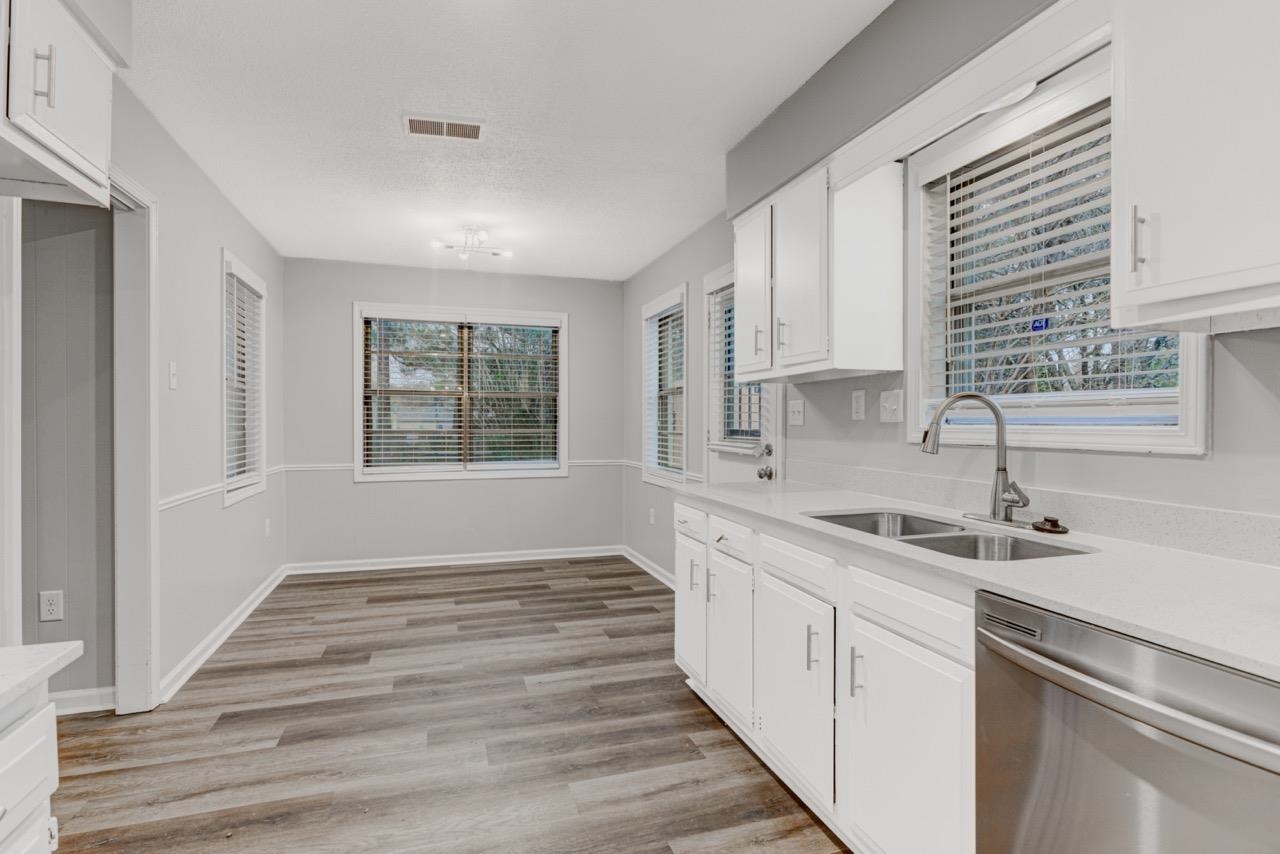 3187 Belle Tower Road Memphis, TN 38115 - Photo 11 of 24 Kitchen with stainless steel dishwasher, light stone countertops, white cabinetry, and light wood-style flooring