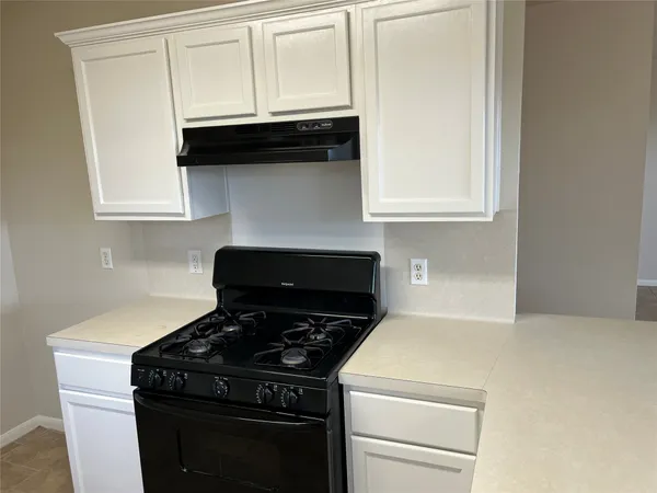 a kitchen with a stove and white cabinets