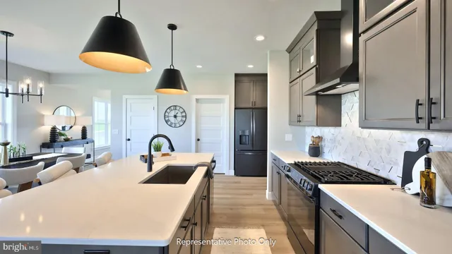 a kitchen with stainless steel appliances granite countertop a stove a sink a refrigerator and a dining table with wooden floor