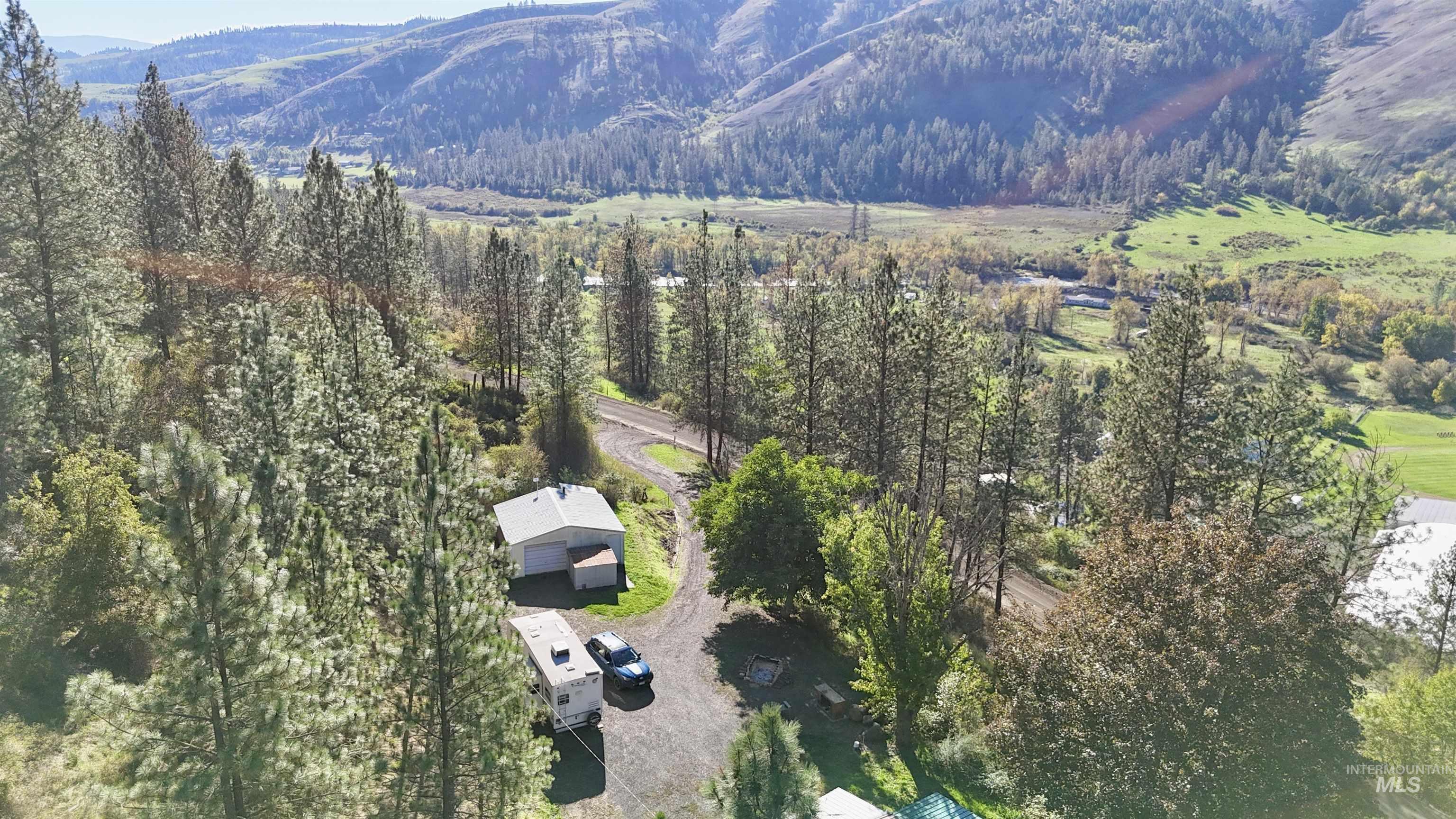 Aerial overview of property's location featuring a mountain backdrop and a heavily wooded area