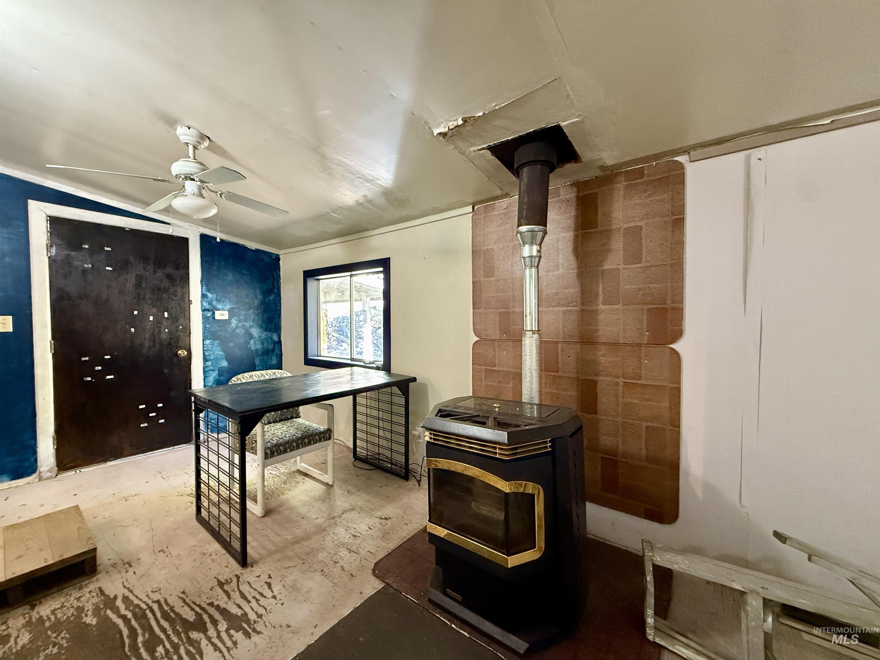 191 Battle Ridge Road Kooskia, ID 83539 - Photo 25 of 35 Office featuring a wood stove, concrete flooring, and a ceiling fan