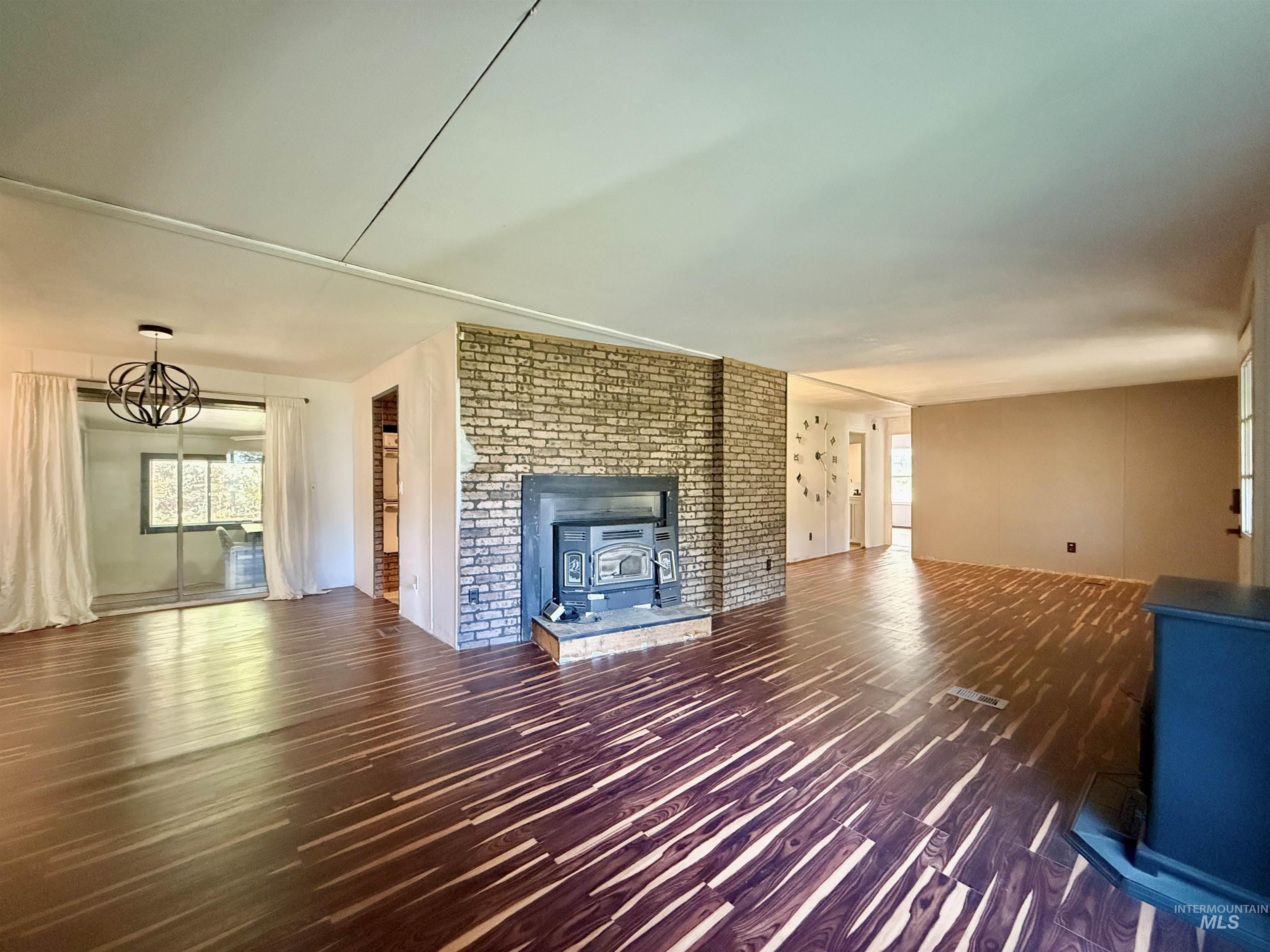 191 Battle Ridge Road Kooskia, ID 83539 - Photo 9 of 35 Unfurnished living room featuring a wood stove, dark wood-style flooring, and a chandelier