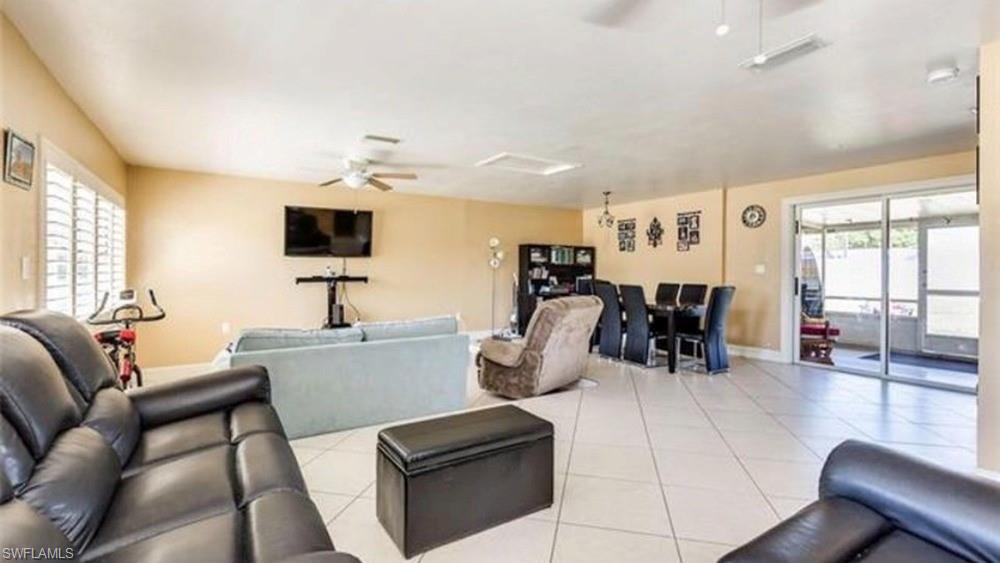 5325 23rd Place Southwest Naples, FL 34116 - Photo 7 of 10 Open-concept living area featuring tile flooring, ceiling fans, and a sliding glass door providing access to an enclosed patio