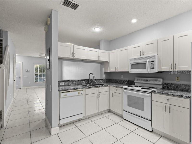 29924 Playa Del Rey Lane Wesley Chapel, FL 33543 - Photo 6 of 31 a kitchen with stainless steel appliances granite countertop a stove and white cabinets