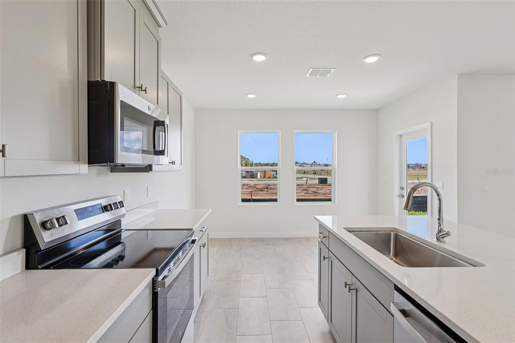 6493 Horseshoe Ln Way St. Cloud, FL 34773 - Photo 8 of 29 a kitchen with stainless steel appliances granite countertop a sink stove and refrigerator
