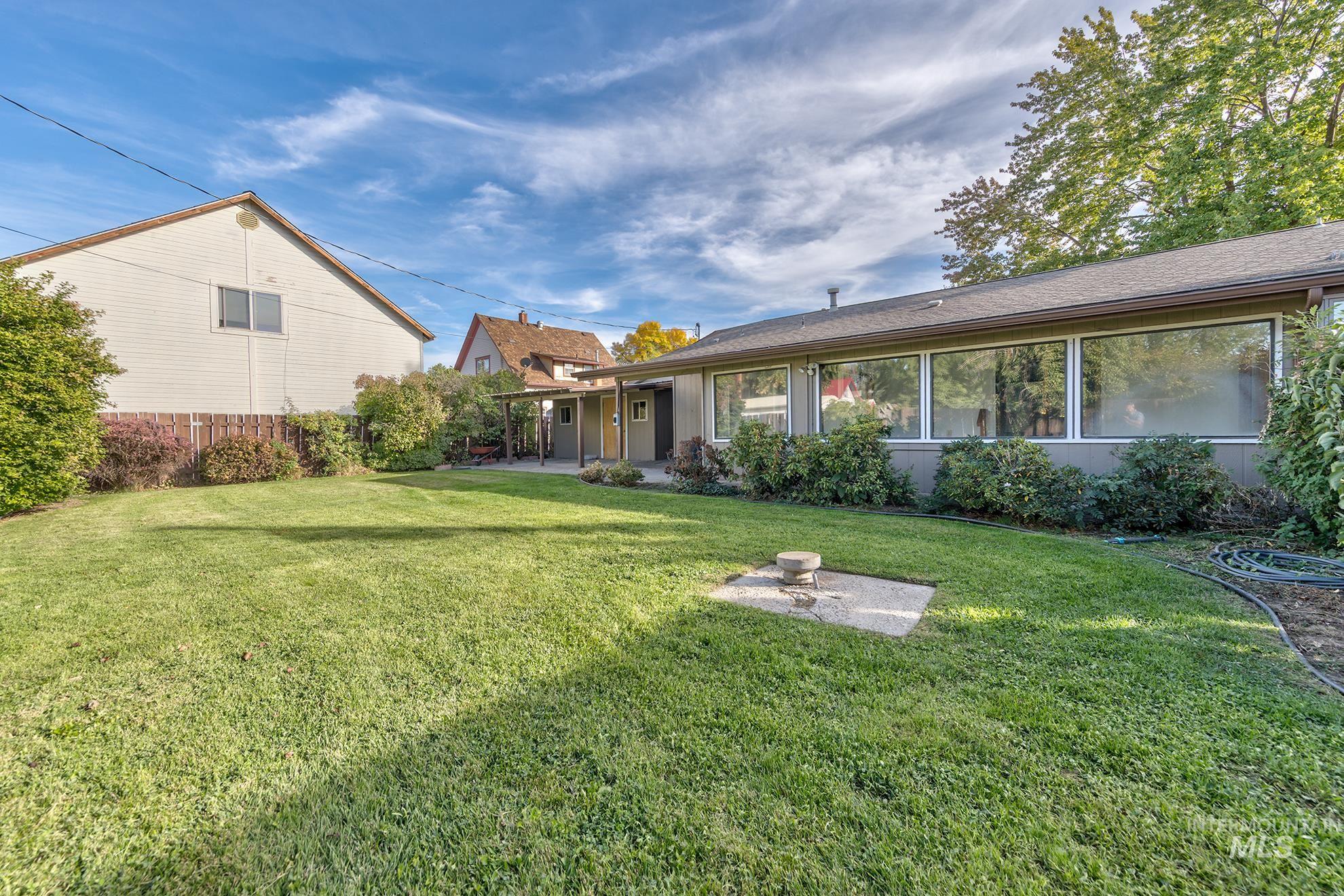 340 Pioneer Road Weiser, ID 83672 - Photo 32 of 44 Expansive lawn area with mature perimeter landscaping, a fenced property boundary, and large exterior windows