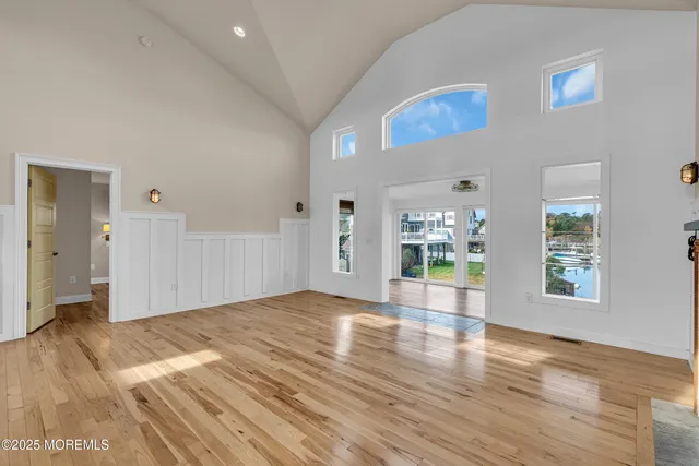 a view of an empty room with wooden floor and a floor to ceiling window