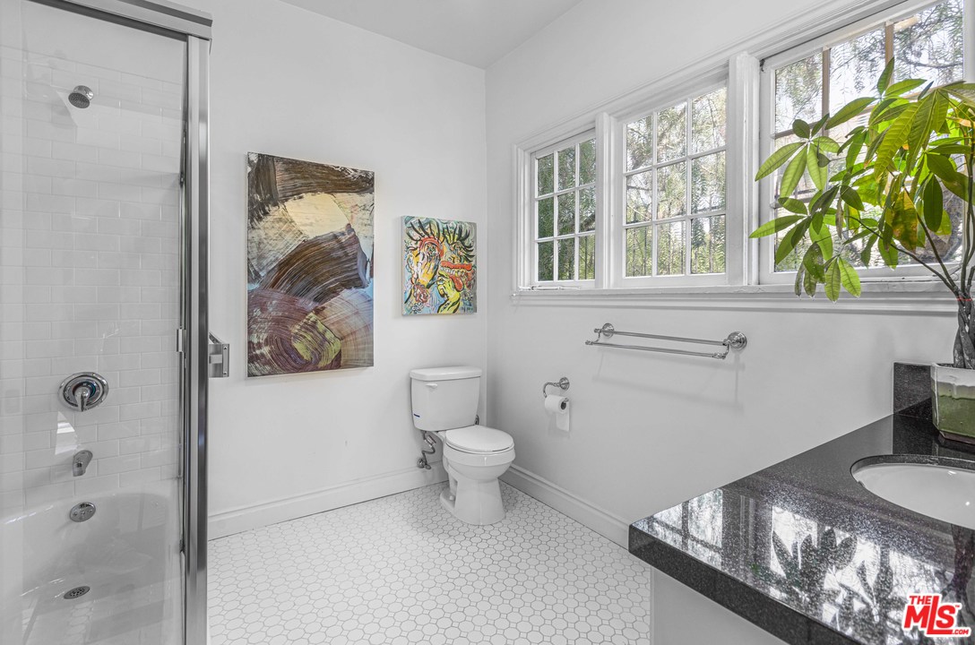 1908 Buckingham Road Los Angeles, CA 90016 - Photo 34 of 39 a bathroom with a granite countertop sink a toilet and a window