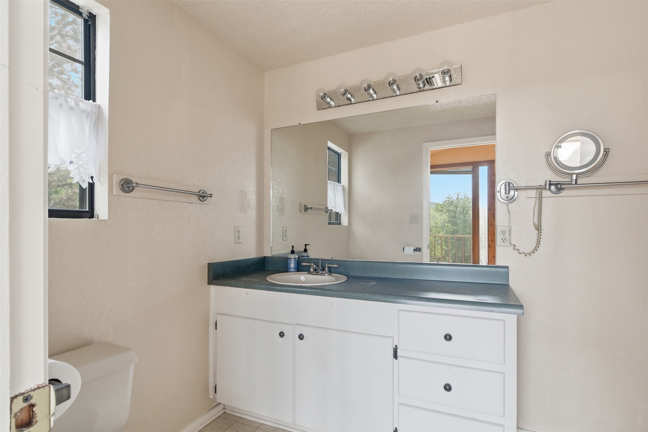 1260 Magers Road Concan, TX 78838 - Photo 20 of 40 A well-lit bathroom features a functional vanity and window, reflecting an outdoor balcony view.