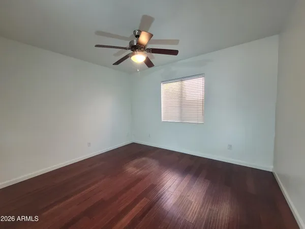 an empty room with wooden floor fan and windows