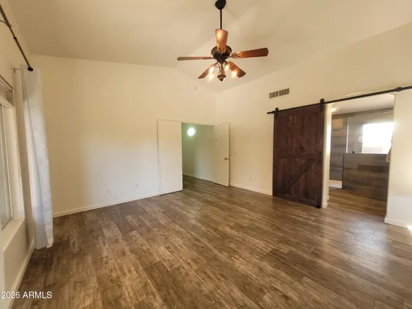 a view of an empty room with wooden floor and a window