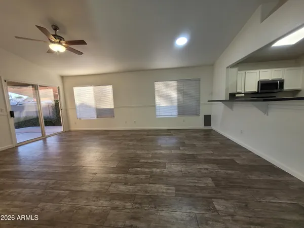 a view of an empty room with window and wooden floor