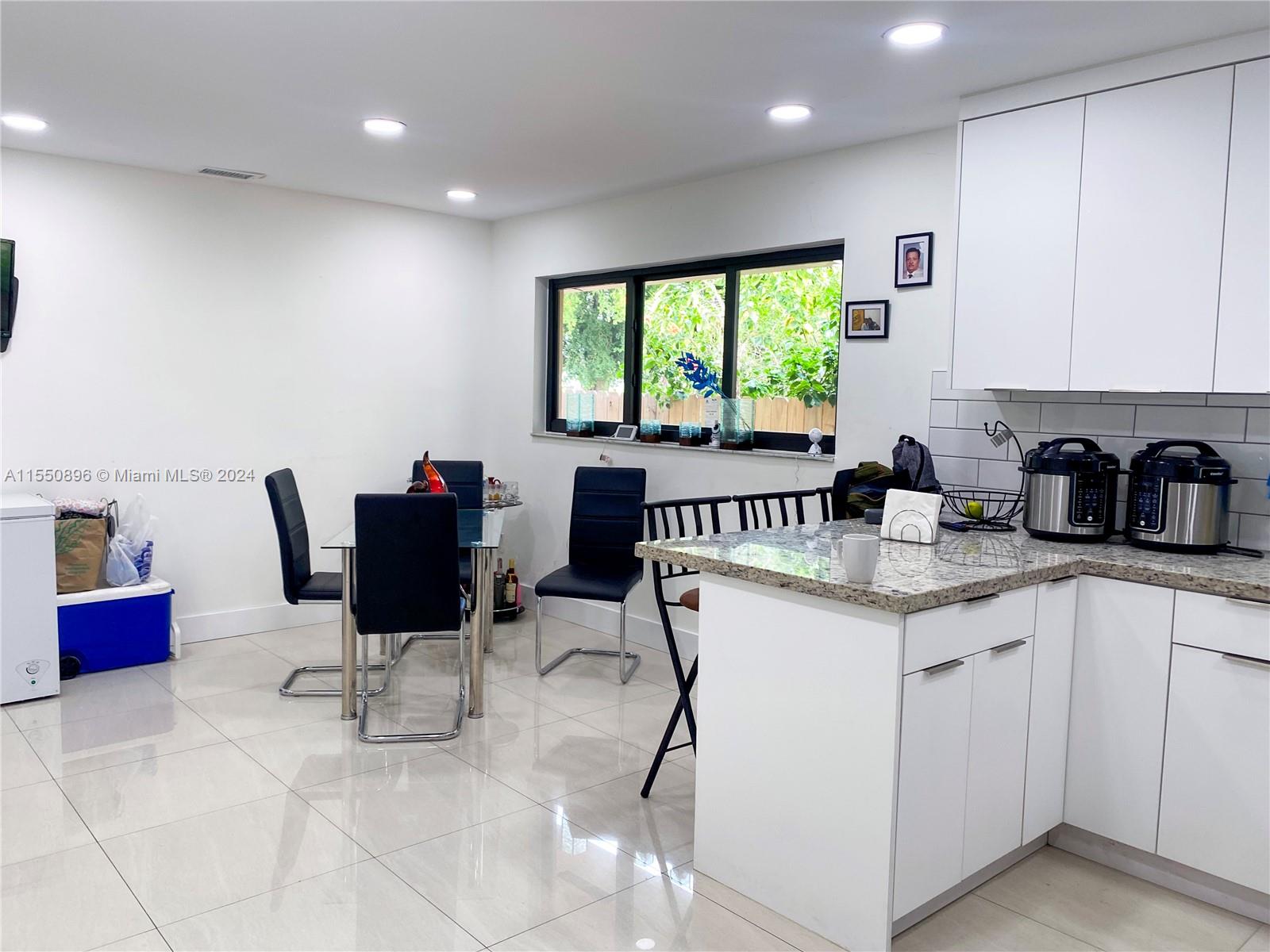 11032 Southwest 5th Street Sweetwater, FL 33174 - Photo 18 of 24 a kitchen with a dining table chairs and white cabinets