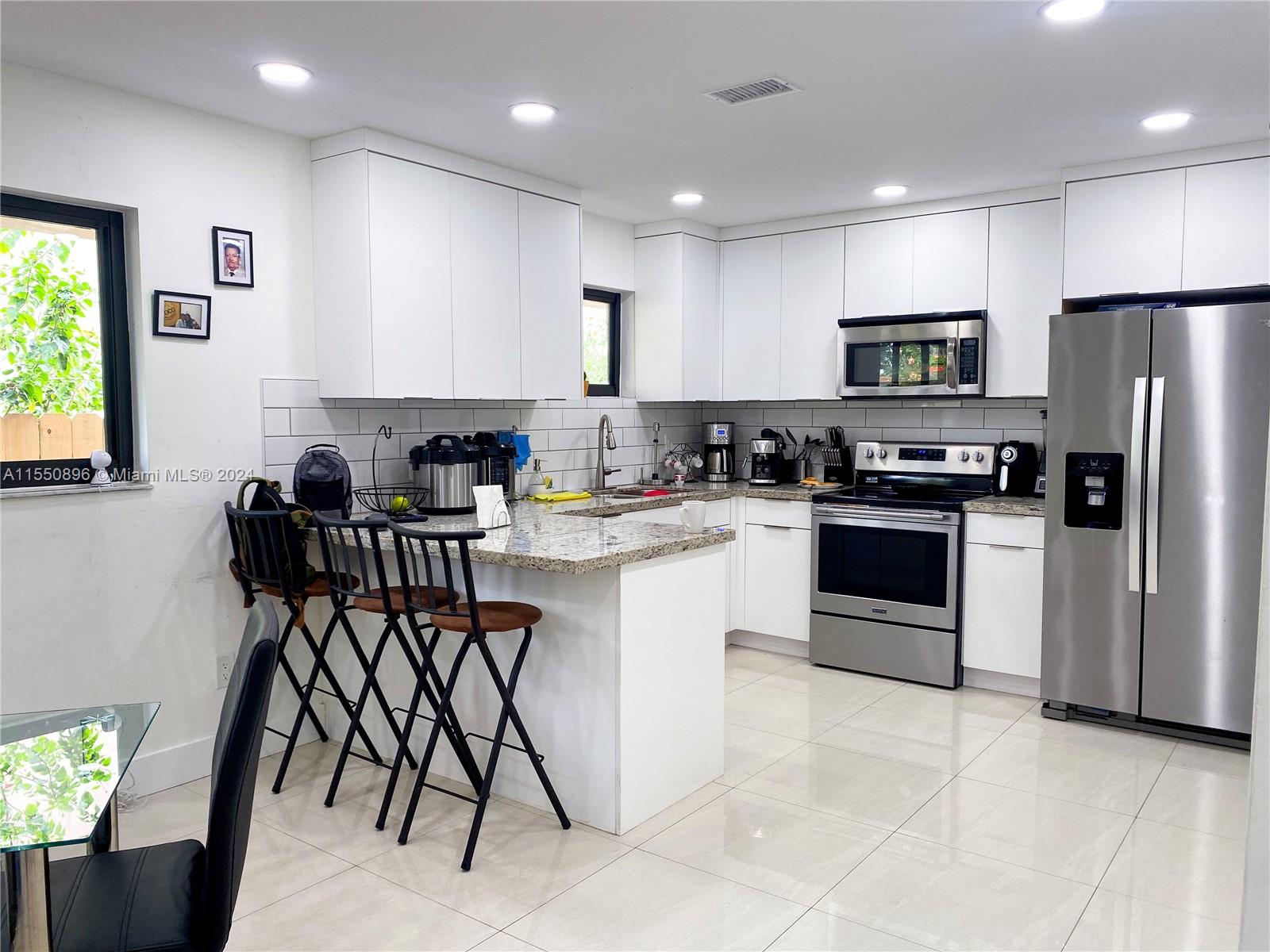 11032 Southwest 5th Street Sweetwater, FL 33174 - Photo 2 of 24 a kitchen with stainless steel appliances granite countertop a stove a sink a microwave a refrigerator and white cabinets
