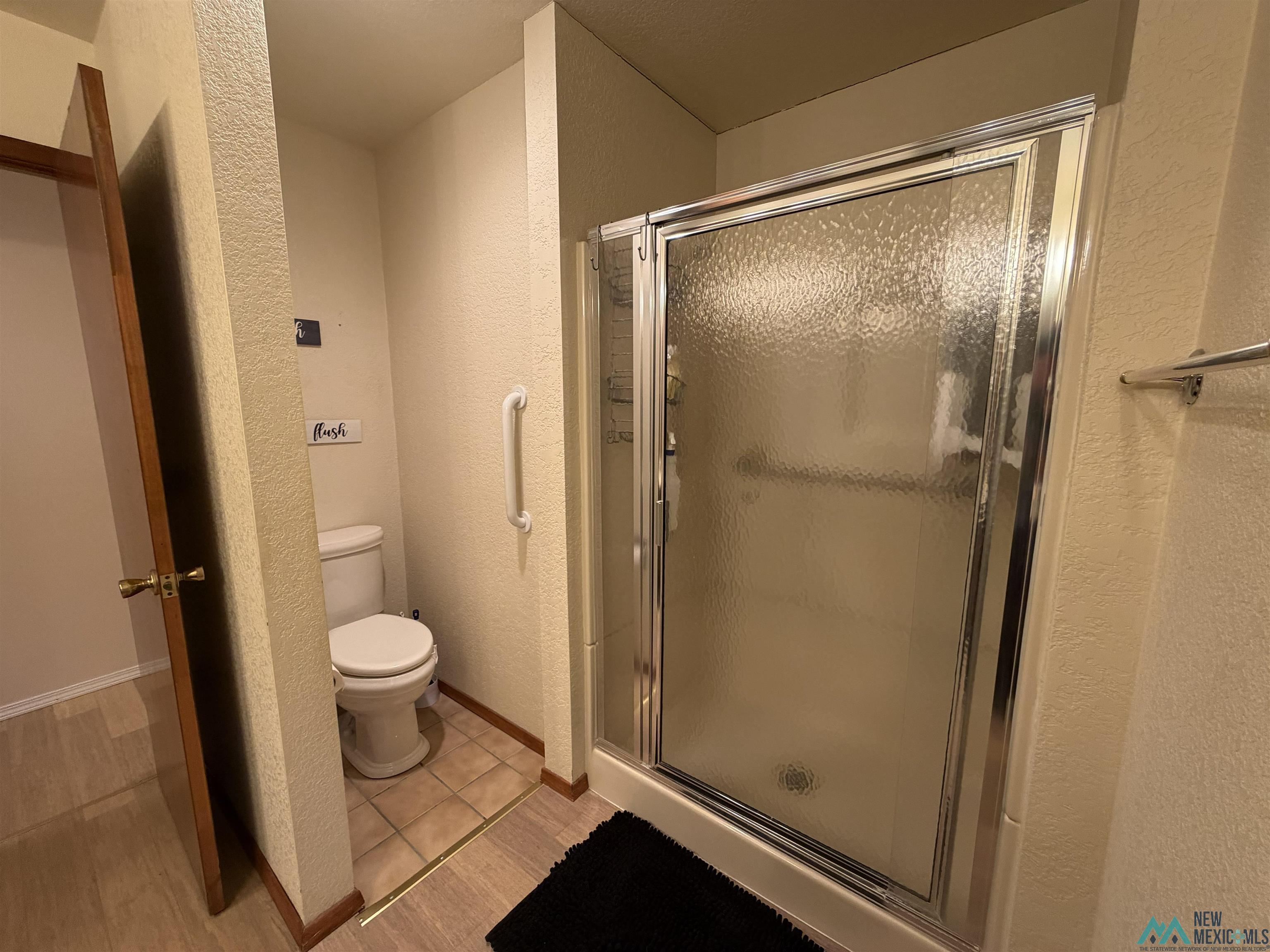 2001 East Derrick Road Carlsbad, NM 88220 - Photo 68 of 84 Full bath with a textured wall, a stall shower, and light tile patterned floors