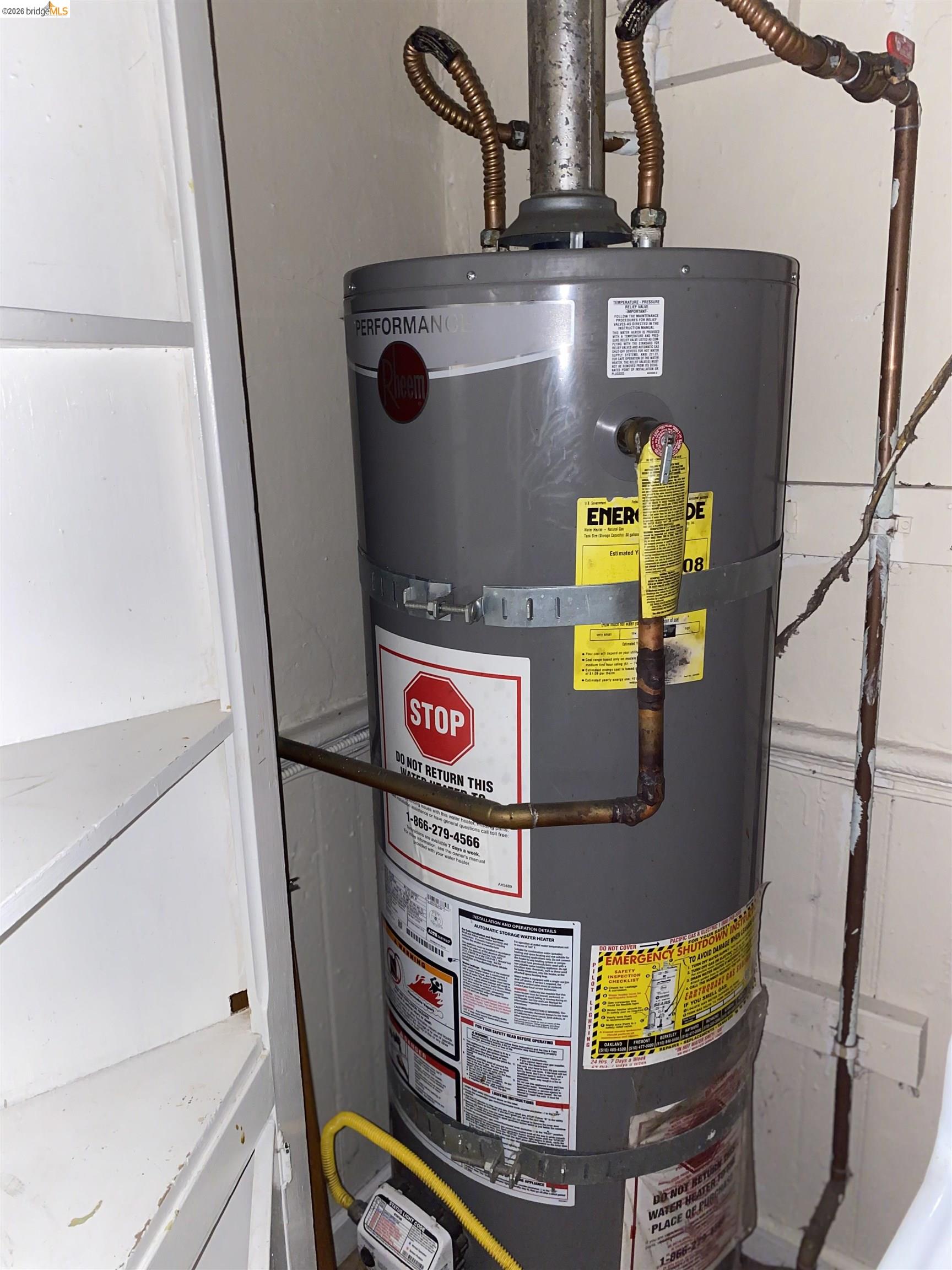 1133 Wood Street Oakland, CA 94607 - Photo 17 of 25 Utility closet featuring a water heater with visible piping and an adjacent built-in shelving unit
