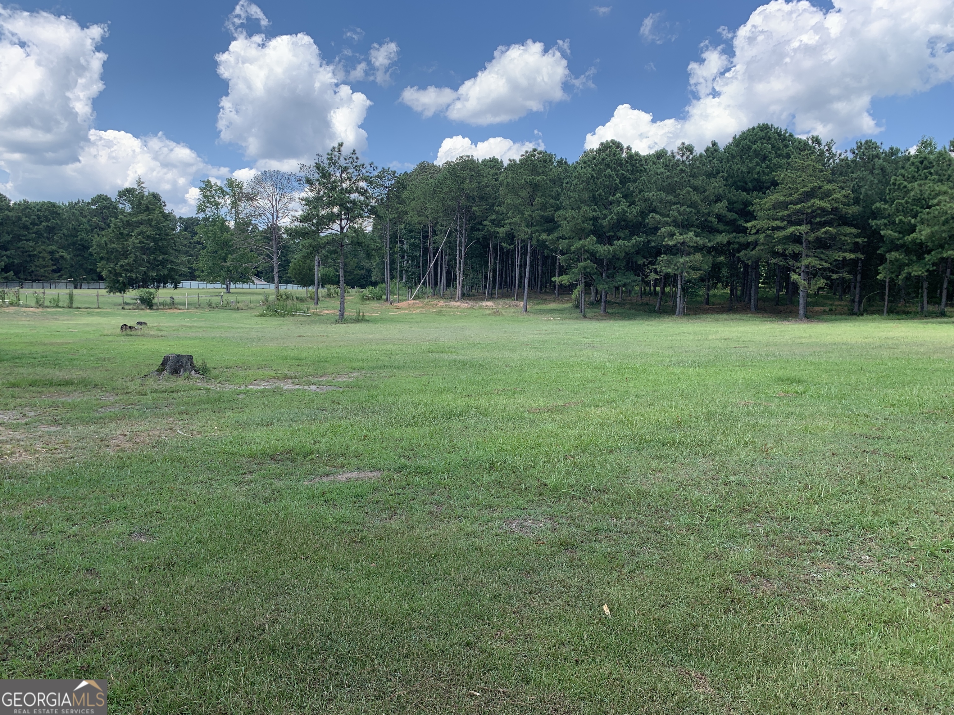 a view of a green field with wooden fence