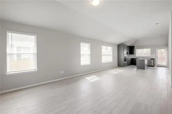 a view of empty room with kitchen and fireplace