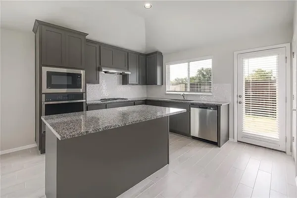 a kitchen with stainless steel appliances granite countertop a sink and a stove