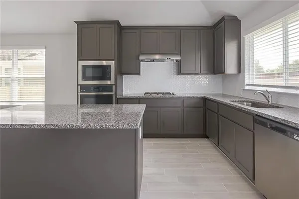 a kitchen with stainless steel appliances granite countertop a sink a stove and a refrigerator